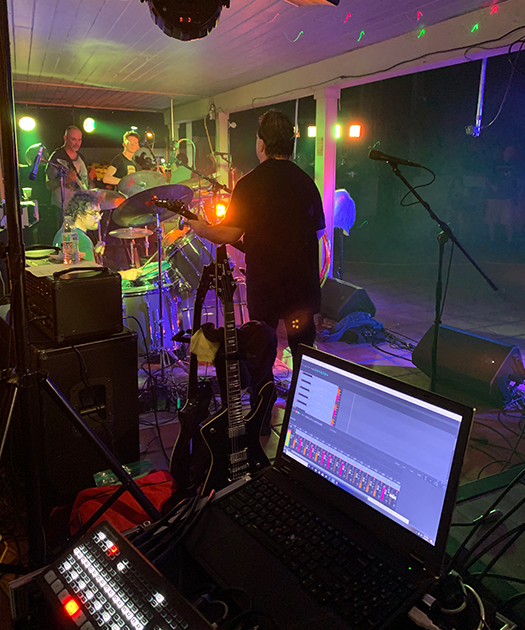 Backstage photo of a livestream setup next to a live rock band